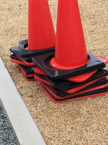 赤い三角コーンに飛散防止のゴム製の重しをしています